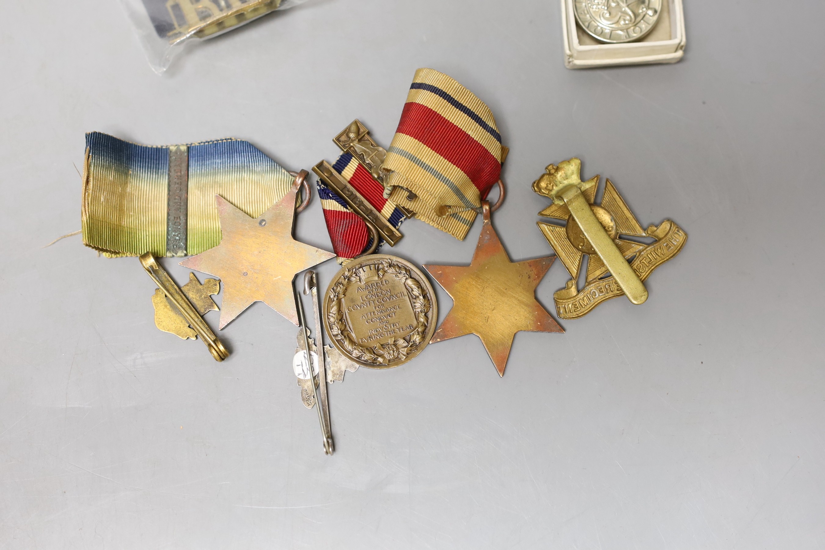 A WWII Atlantic Star, Africa Star, WWI The Kings Medal, German Signal Flag Tinnies, cap badges, etc.